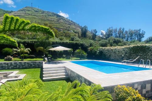 a swimming pool in a garden with a hill in the background at flAle's holiday house in Cefalù
