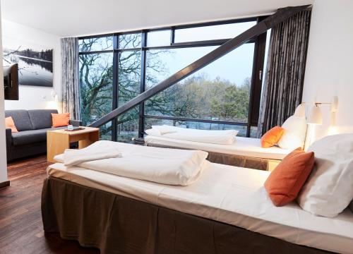drie bedden in een kamer met een groot raam bij Vingsted Hotel & Konferencecenter in Bredsten