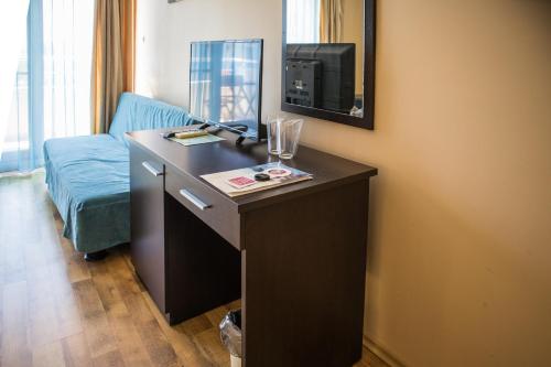 a room with a desk with a tv and a couch at Hotel Buena Vissta in Primorsko