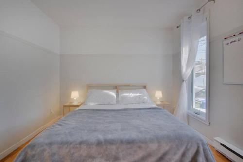 a bed in a room with two lamps and a window at Cozy home with hot tub near airport in Quebec City