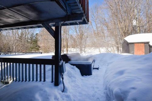 a yard covered in snow next to a porch at Cozy home with hot tub near airport in Quebec City