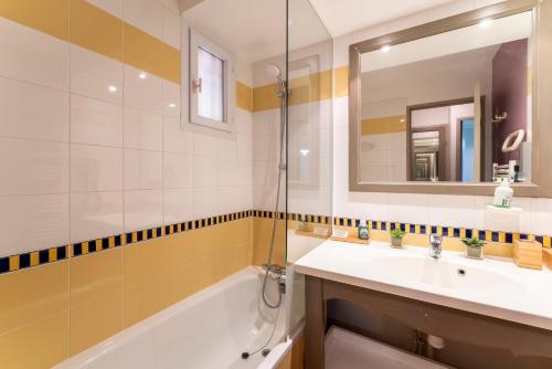 ein Badezimmer mit einem Waschbecken, einer Badewanne und einem Spiegel in der Unterkunft T2 Accès direct golf et piscine in Mallemort