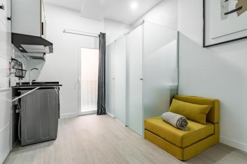 a living room with a yellow chair and a kitchen at Sol Apartment III - En el centro de Madrid in Madrid