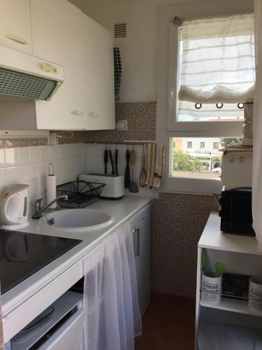 une petite cuisine avec un évier et une fenêtre dans l'établissement Studio avec terrasse face plage parking, au Barcarès