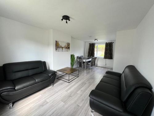 a living room with a black couch and a table at 3-Bedroom Cosy Reading House in Reading