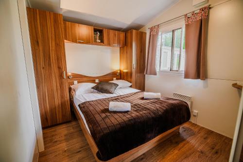 1 dormitorio con 1 cama con 2 toallas en Lake View Mobile Homes with Thermal Riviera Tickets in Terme Čatež, en Čatež ob Savi