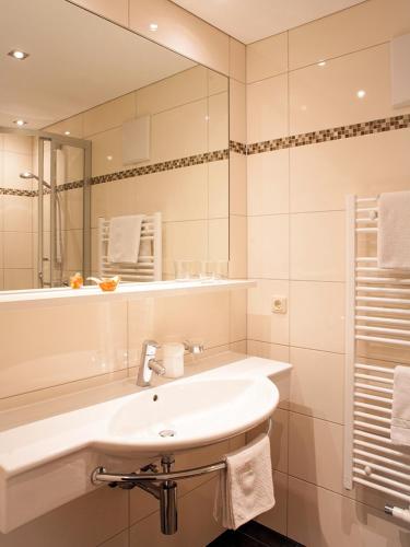 a white bathroom with a sink and a mirror at Pension Waldhof in Lech am Arlberg