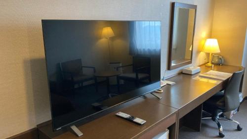 a large flat screen tv on a desk in a hotel room at Castle Inn Toyokawa in Toyokawa