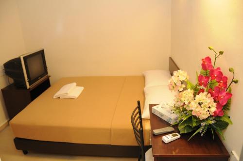 ein Hotelzimmer mit einem Bett und einem Tisch mit Blumen in der Unterkunft Desaru Penawar Inn in Desaru