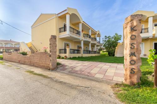 a house with a sign on the side of the road at Kosmos Hotel St7 in Agios Stefanos in Agios Stefanos