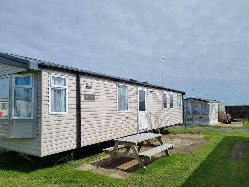 a small white trailer with a bench next to it at Red Lion Holiday Park in Arbroath