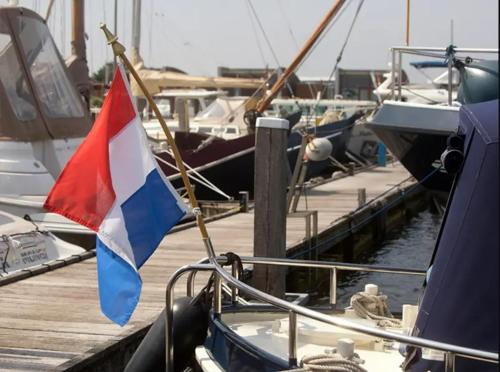 a flag on a boat at a dock with other boats at Marina VILLA nabij water met prive sauna. in Spakenburg