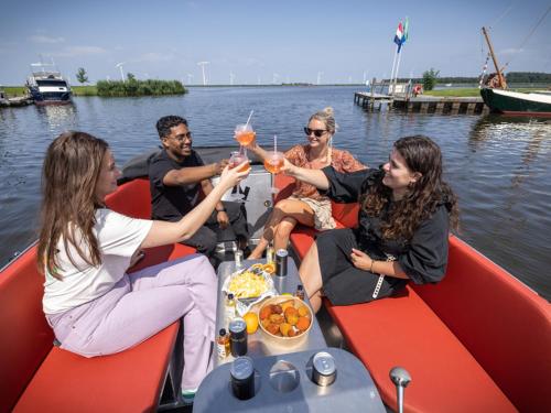 a group of people sitting on a boat with drinks at Marina VILLA nabij water met prive sauna. in Spakenburg