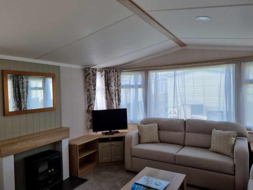 a living room with a couch and a tv at Red Lion Holiday Park in Arbroath