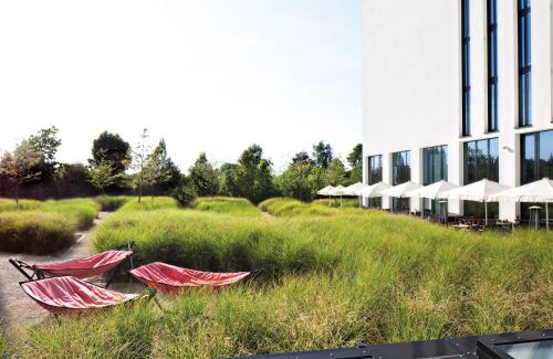 a row of red canoes in a field next to a building at Leonardo Royal Hotel Munich in Munich