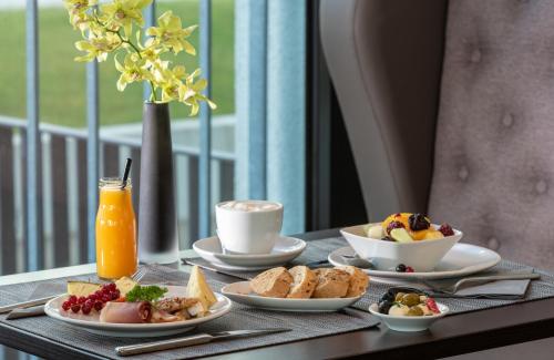 a table with plates of breakfast foods and a drink at Leonardo Royal Hotel Munich in Munich