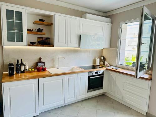 a kitchen with white cabinets and a sink and a window at Sunset Appartment in Golem