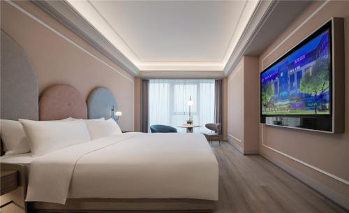 a hotel room with a large bed and a flat screen tv at Mercure Suzhou Shilu Shantang in Suzhou