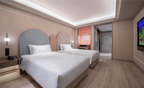 two beds in a hotel room with a tv at Mercure Suzhou Shilu Shantang in Suzhou