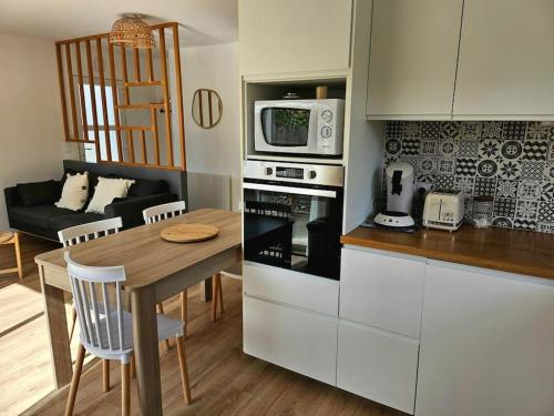 a kitchen and dining room with a table and a microwave at Le Petit Rocher in Saint-Jean-de-Monts