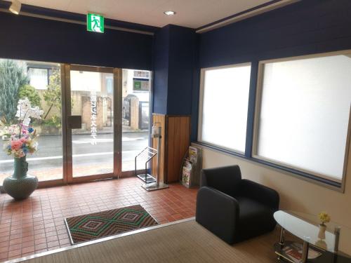 a lobby with a waiting room with a chair and windows at Business Hotel Azuma in Hanno