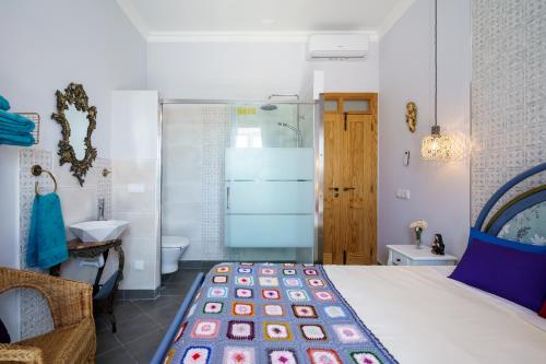 a bedroom with a bed and a bathroom with a sink at Casa D'Nossa, casa tradicional e Moderna, vista 360º, piscina de agua salgada in Luz de Tavira