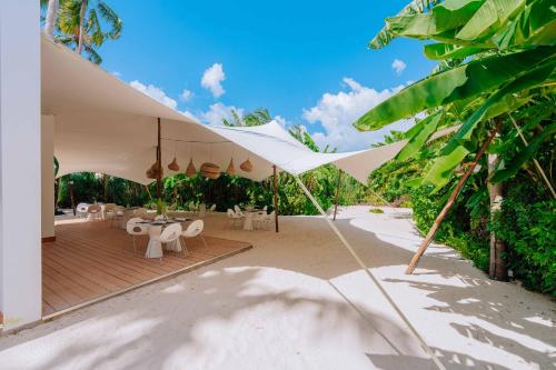 a patio with white umbrellas and tables and chairs at Ycona Eco-Luxury Resort, Zanzibar in Dikoni
