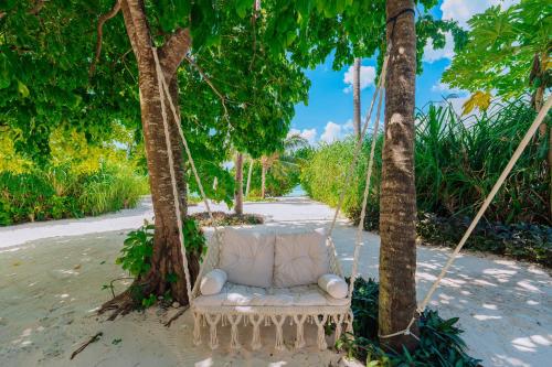 a white couch hanging from trees on a beach at Ycona Eco-Luxury Resort, Zanzibar in Dikoni