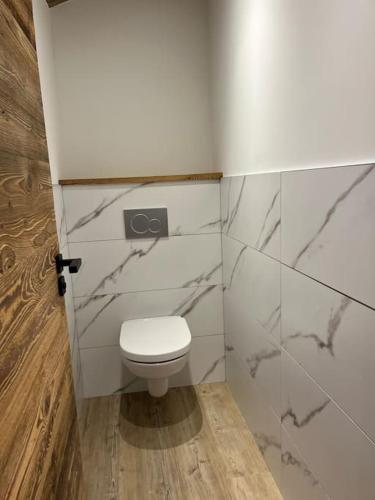 La salle de bains est pourvue de toilettes blanches et de murs en marbre. dans l'établissement Appartement cosy rénové, à Megève