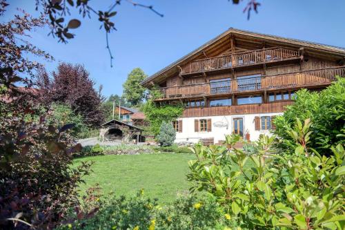 une grande maison en bois avec une pelouse devant elle dans l'établissement Ferme du Ciel, à Samoëns