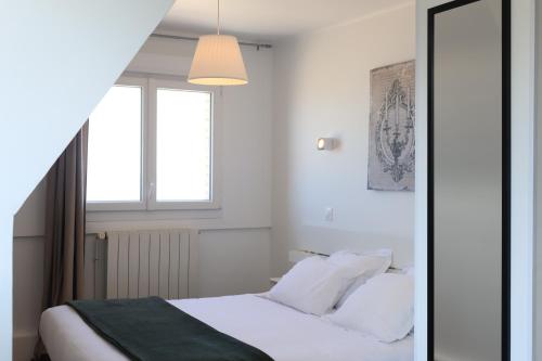 a bedroom with a bed with white sheets and a window at Le Clos Normand in Saint-Aubin-sur-Mer
