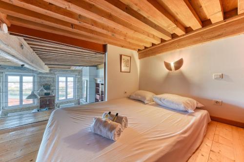 Cama grande en habitación con techo de madera en GuestReady - Canut Typique avec vue sur Lyon, en Fourvière