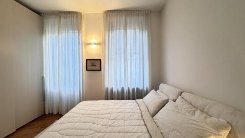 米蘭的住宿－Milano Sempione Apartament，卧室配有白色的床和2扇窗户。