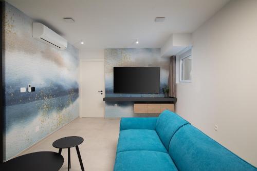 a living room with a blue couch and a tv at Villa Estrella in Medulin for 10 people with sauna & whirpool just 6 m from the sea in Medulin
