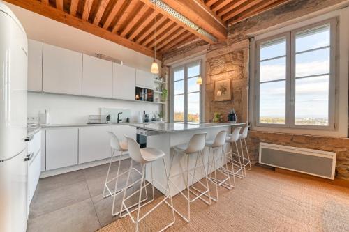 une cuisine avec des armoires blanches et des tabourets de bar dans l'établissement GuestReady - Canut Typique avec vue sur Lyon, à Lyon