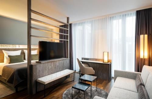 Habitación de hotel con cama y TV en Leonardo Royal Hotel Munich en Múnich