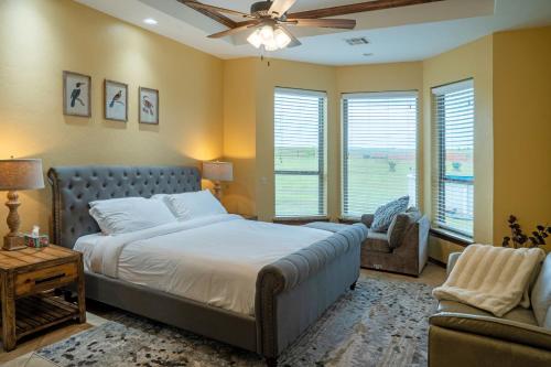 ein Schlafzimmer mit einem Bett, einem Sofa und Fenstern in der Unterkunft Peaceful Luxurious Ranch Family Reunion in Wanette