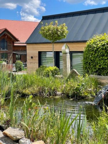 ein Haus mit einem Teich vor einem Haus in der Unterkunft Tinyhaus Supreme für 1-4 Personen in Fuchsmühl