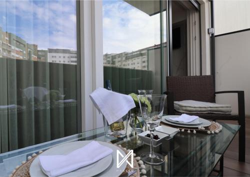 a glass table with plates and glasses on a balcony at MyStay - D Maria Apartments in Vila Nova de Famalicão