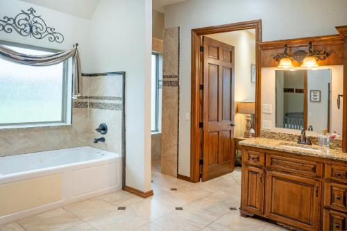 ein Badezimmer mit einer Badewanne, einem Waschbecken und einem Spiegel in der Unterkunft Peaceful Luxurious Ranch Family Reunion in Wanette
