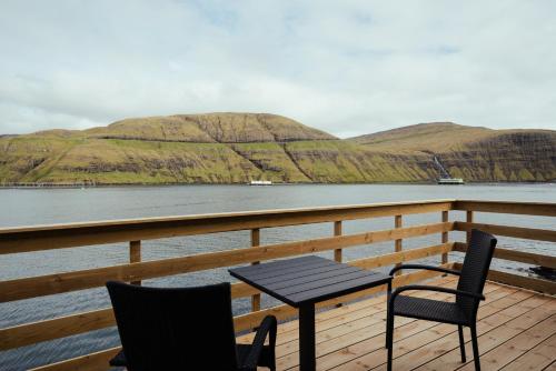 a table and chairs sitting on a deck overlooking a body of water at Seadreams Nest - Luxurious Waterfront Retreat in Vestmanna