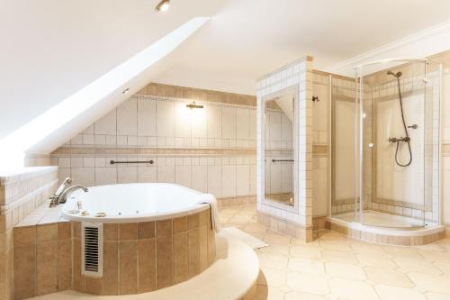 y baño grande con bañera y ducha. en Apartamenty w Dworku Cheval en Cracovia