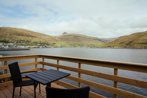 a table and chairs sitting on a deck next to a body of water at Seadreams Nest - Luxurious Waterfront Retreat in Vestmanna