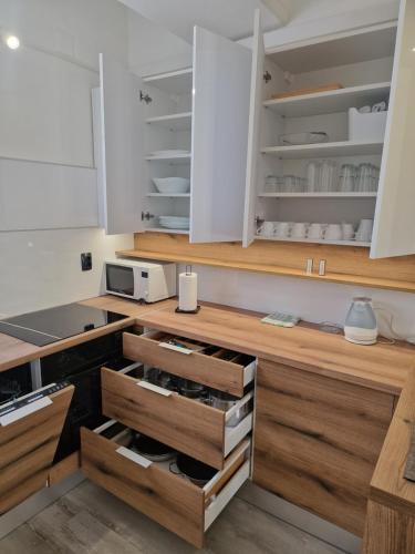 a kitchen with white cabinets and wooden drawers at Cozy apartment near beach in Gajac in Skunca