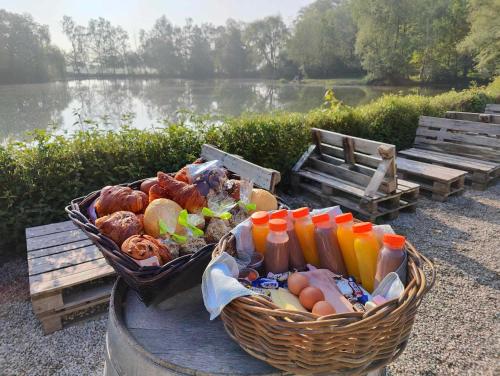 een mand met eten op een tafel naast een meer bij Prullenbos Tiny Nutz Nest in Wetteren