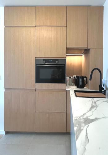 une cuisine avec des armoires en bois et un four à micro-ondes dans l'établissement Appartement 2 pièces 30min du centre de Paris, à Clichy