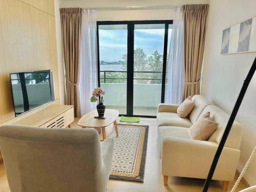a living room with a couch and a tv at Mutiara Melaka Beach Resort by Glex in Tangga Batu