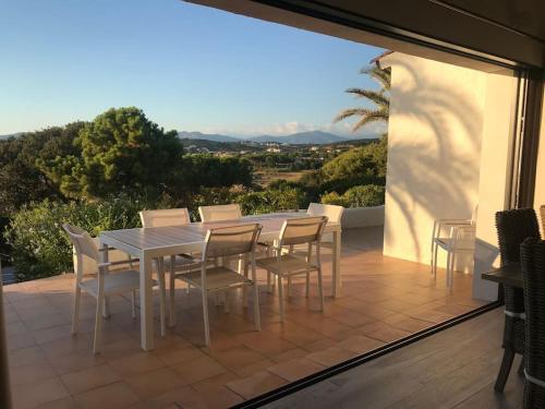 Une table à manger et des chaises blanches sont disponibles sur la terrasse. dans l'établissement Villa Sampiero, sur mer, piscine et plage à pieds, à Pietrosella