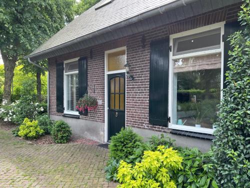 dom z czerwonej cegły z czarnymi drzwiami i oknem w obiekcie Nisterlo Guesthouse w mieście Nistelrode