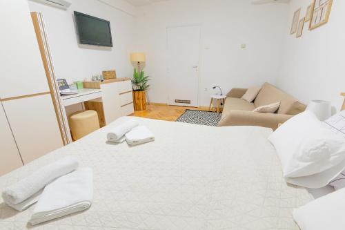 a white room with a bed and a living room at Apartman Lumi in Čakovec